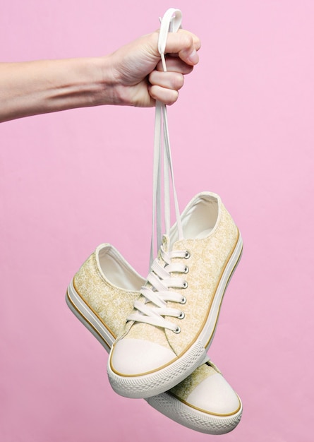 Premium Photo | Close up on hand holding sneakers by shoelaces