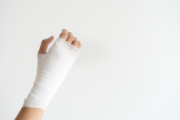 白い壁に包帯で痛みを伴う手を閉じます 医師による医療女性の骨折治療の手 プレミアム写真