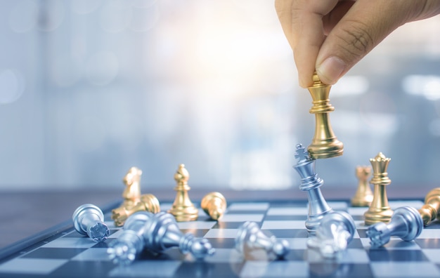 Close up hand playing chess and win in board game, strategy and planning business concept Premium Ph