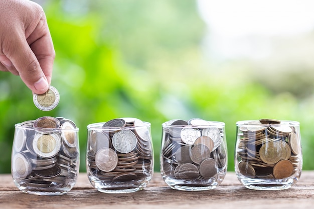 Close up hand putting coins into clear money jar Premium Photo