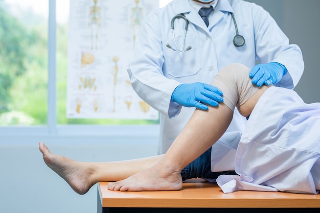 Close-up hand wear medical gloves doctor examining head of patient with knee problems in clinic. Premium Photo