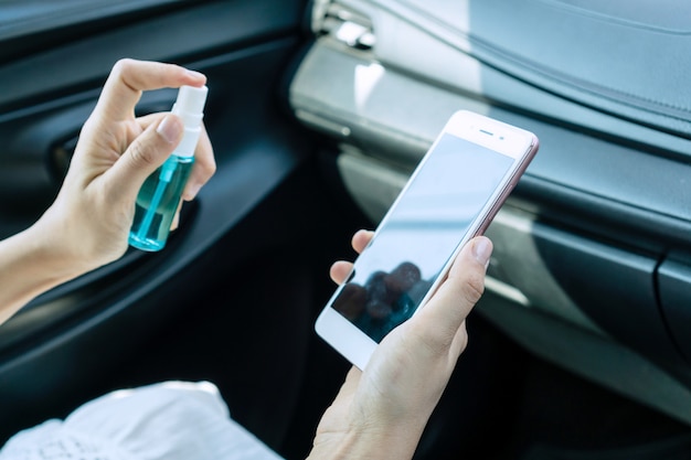 Premium Photo | Close up hand of woman disinfecting smart phone by spraying alcohol from a bottle, protection against infectious virus, bacteria and germs. coronavirus/ covid-19, health care concept.