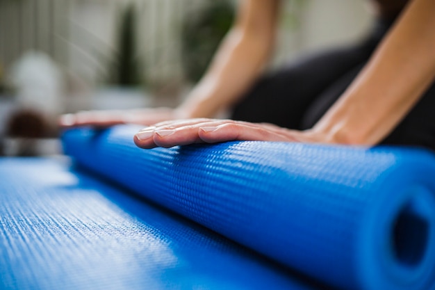 Close Up Hands Rolling Up Yoga Mat Free Photo