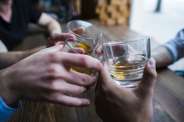 Free Photo | Close-up of hands toasting whisky glasses