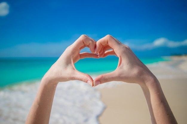 Premium Photo | Close up of heart made by female hands in the beach