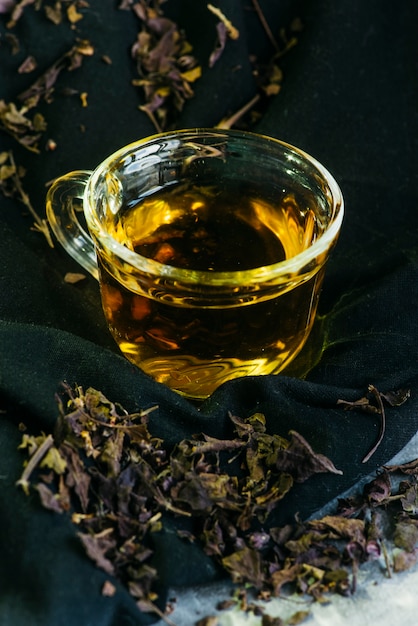 Close-up of herbal tea in glass cup with dried tea leaves Free Photo