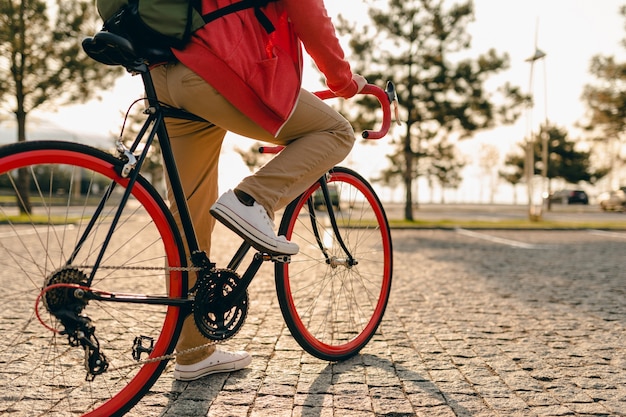 スニーカーで足を閉じ、赤いパーカーとベージュのズボンでヒップスター 