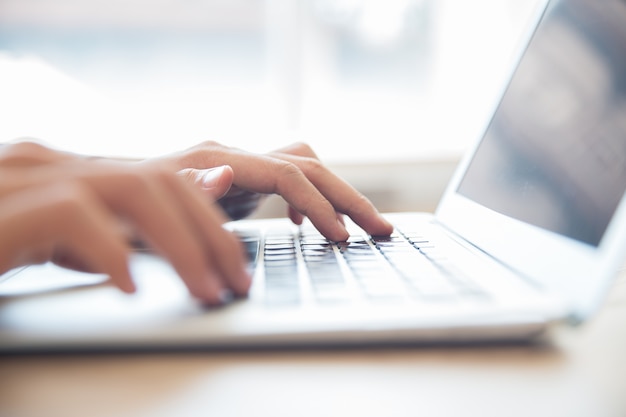 Close-up of male hands typing on laptop keyboard Free Photo