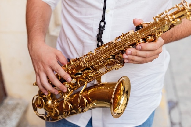 Premium Photo | Close up of a man holding his saxophone on the street