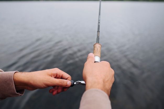 Free Photo Close Up Of Man S Hand Holding Fishing Rod Over The Lake