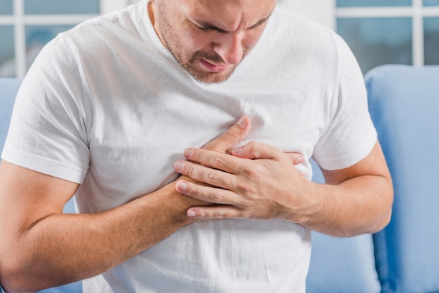 Close-up of a man with heart attack symptoms touching his heart with two hands Free Photo