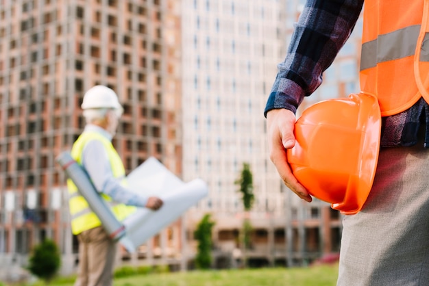 Close-up man with safety vest holding helmet Free Photo