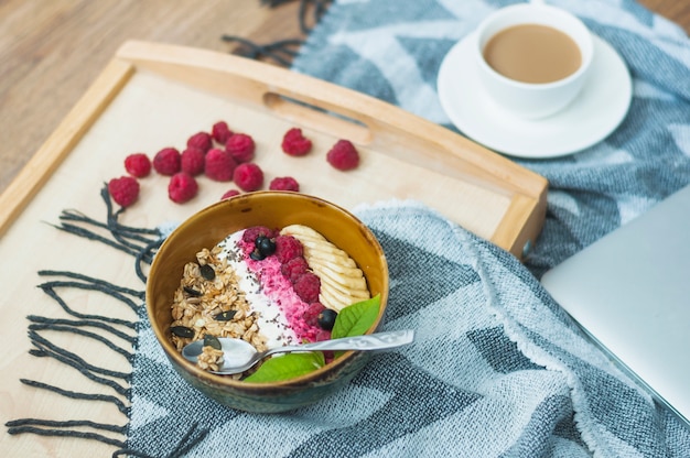 Close-up of oatmeal bowl with raspberries on wooden tray Free Photo