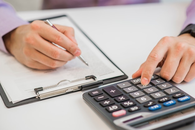 Close-up Of Businessman Calculating Invoices Using Calculator Free Photo Close-up Of Businessman Calculating Invoices Using Calculator Free Photo