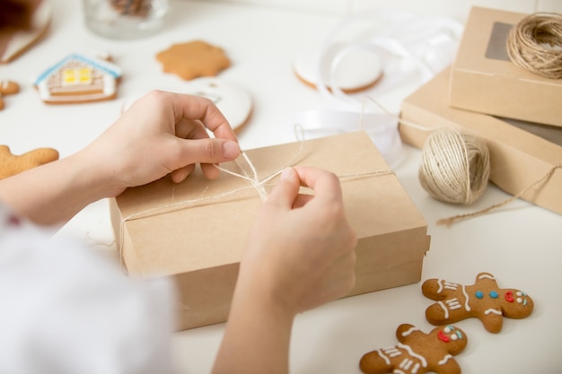 Close up of confectioner hands wrapping a cardboard box Free Photo