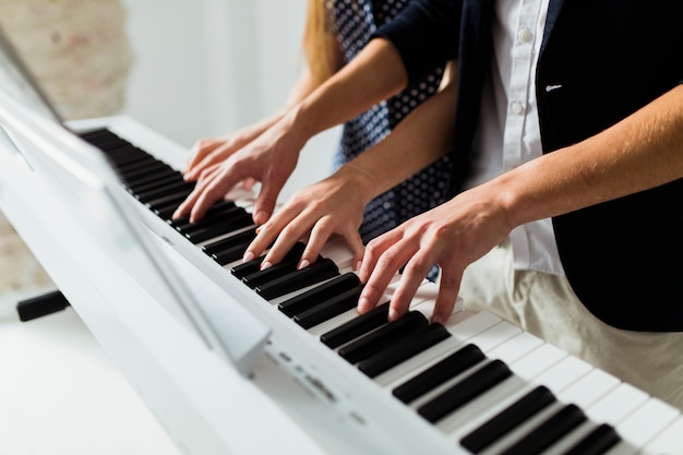 ピアノの鍵盤を弾くカップルの手のクローズアップ 無料の写真