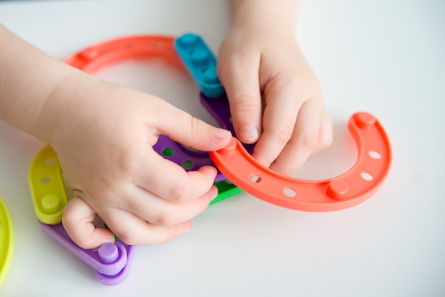 明るいプラスチックのおもちゃのコンストラクタを遊んでいる子供の手のクローズアップ 創造的な赤ちゃんは新しい形を作ります コピースペース プレミアム写真