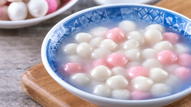 冬至の祭りの食べ物のための青いボウルに赤と白の湯円湯円もち米団子ボールのクローズアップ Premium写真
