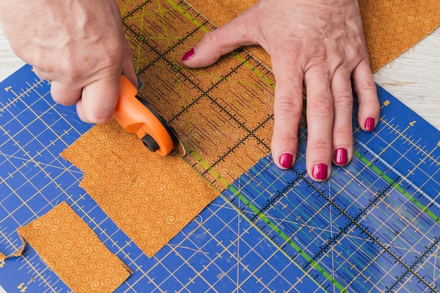 Download Free Photo | Close-up of a person cutting fabric pieces by rotary cutter on mat using ruler