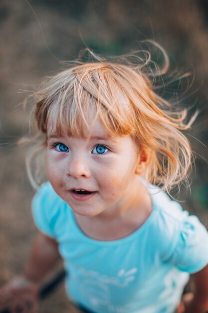 Close Up Portrait Of Little Blonde Girl With Blue Eyes Outside