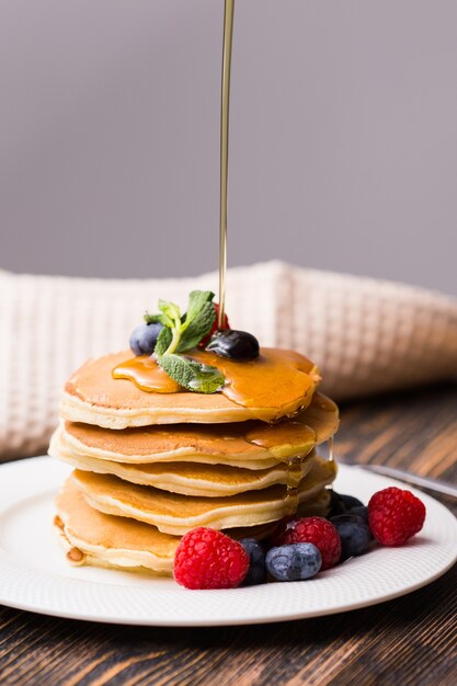 Premium Photo | Close-up of pouring maple syrup on stack of pancakes.