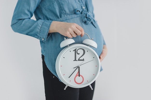 Close-up of pregnant woman showing clock | Premium Photo