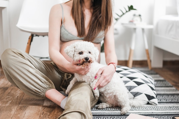 Close-up of pregnant woman with her lovely white toy poodle sitting on floor Free Photo
