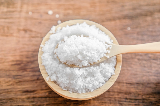 Close up salt in bowl with spoon on wooden table Premium Photo