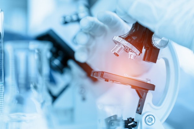 Close up scientist using microscope in laboratory room while making medical testing and research Premium Photo