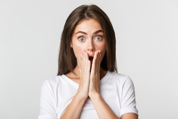 Premium Photo | Close-up of shocked gasping brunette girl cover mouth ...