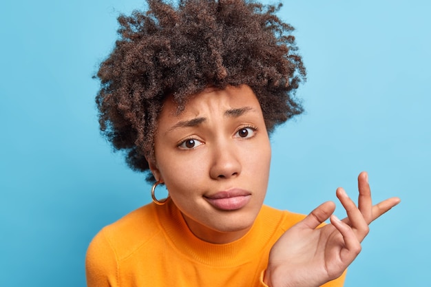 Premium Photo | Close up shot of curly haired confused woman shrugs ...