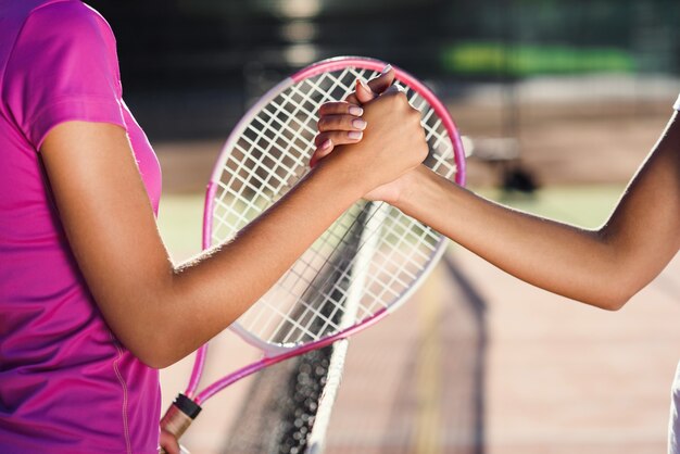Close Up Shot Of A Two Young Female Tennis Players Shaking Hands Over The Net Friendly Handshake After The End Of The Tennis Tournament Premium Photo