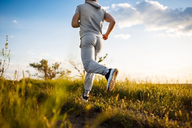 Free Photo Close Up Of Sportive Man Jogging In Field At Sunrise