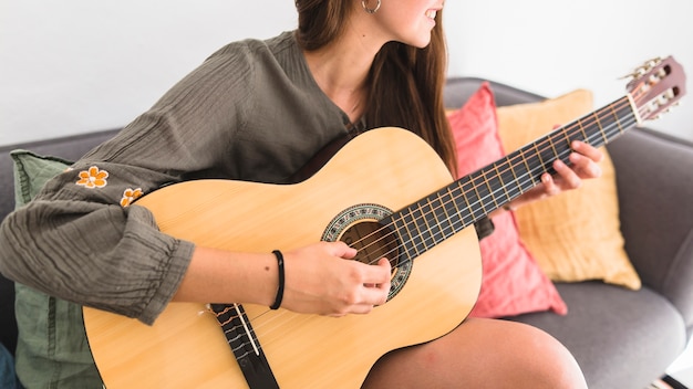 Free Photo Close Up Of A Teenage Girl Sitting On Sofa Playing Guitar At Home