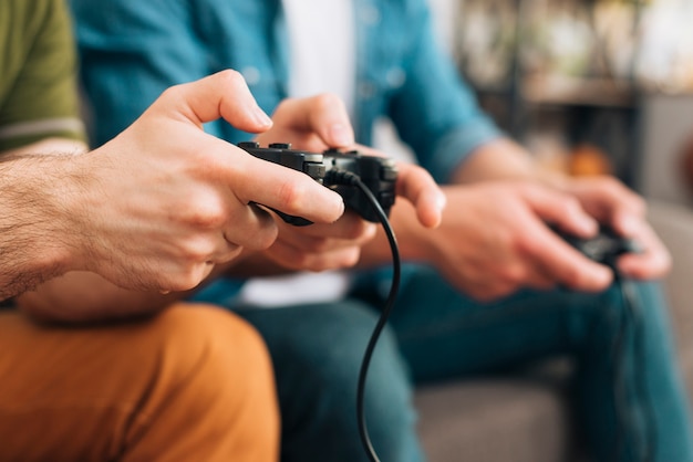 Close-up of two young men holding a black game controller | Free Photo