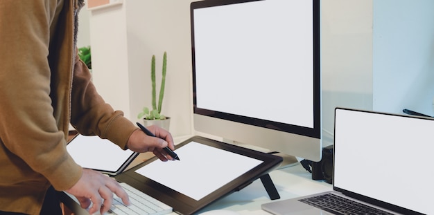 Close-up view of professional male graphic designer working on his pro jet with blank screen digital tablet Premium Photo
