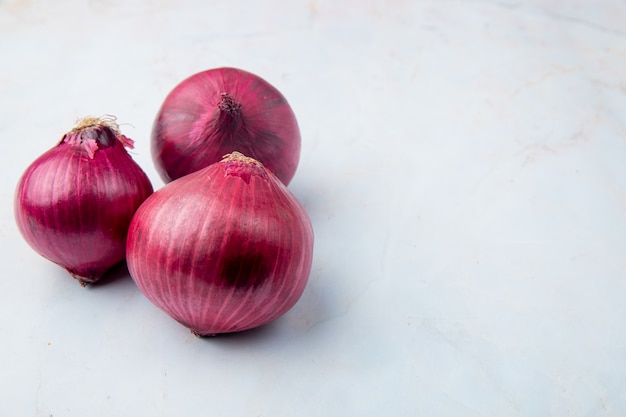 Close-up view of whole red onions on left side and white background with copy space Free Photo