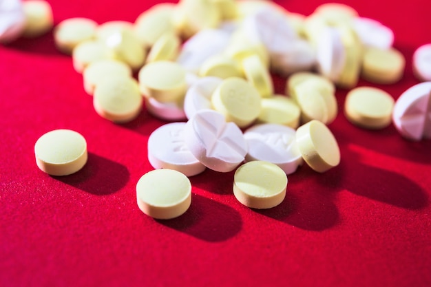 Close-up of white and yellow pills on red background Free Photo