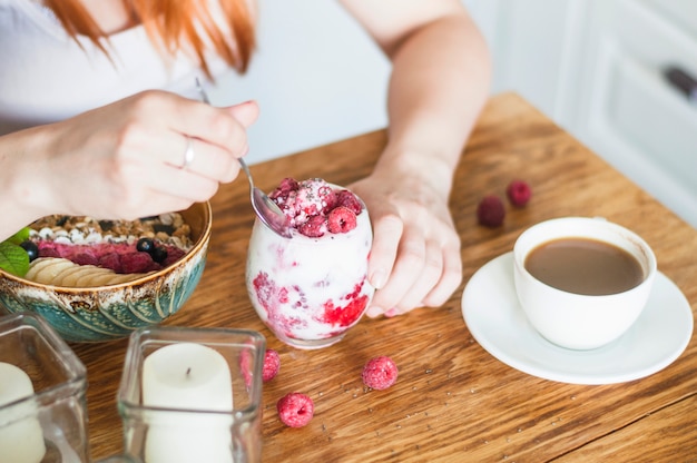 Closeup Of Woman Eating Yogurt With Raspberry On Wooden Table Free Photo