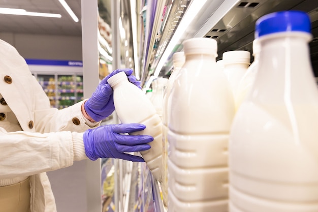 Close Up Of Woman Hands In Medical Gloves Chooses Milk Products By