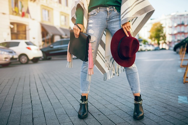 Close up of woman legs wearing black leather boots, jeans, footwear spring trends, holding bag Free Photo