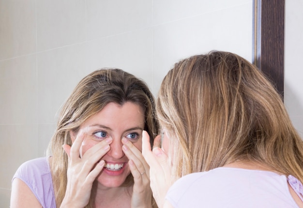 Close-up of woman looking at her face in the mirror Free Photo
