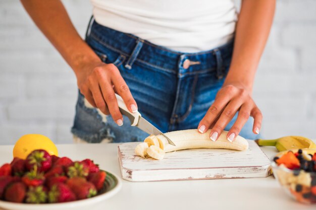 Free Photo | Close-up of woman's hand cutting ripe banana on board