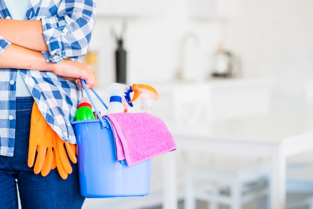 Close-up of woman's hand holding bucket with cleaning supplies and pink napkin Premium Photo