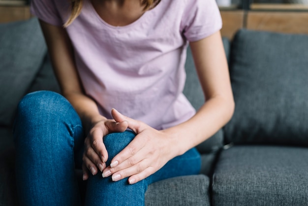 Close-up of a woman's hand touching her knee | Free Photo