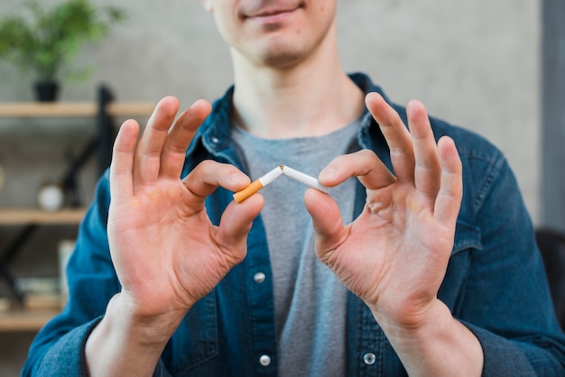 Close-up of young man holding broken cigarette Premium Photo