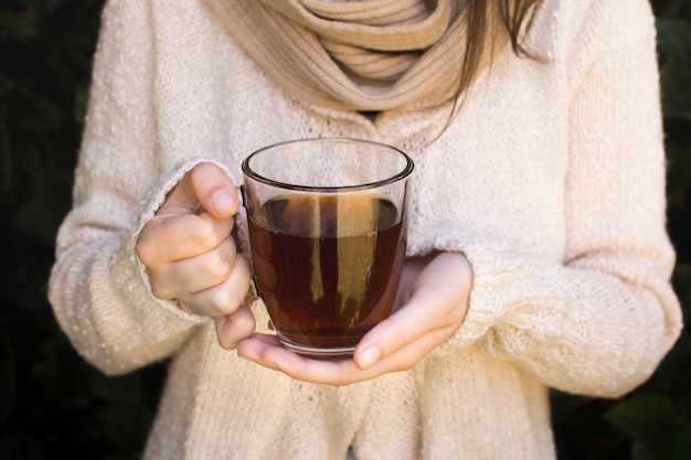 Close-up of a young woman holding transparent cup of herbal tea Free Photo