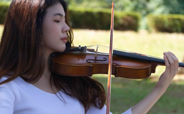 クローズアップ美しい女性が興味を持ってバイオリンを弾く モデルのポーズの肖像画 周りのぼやけた光 プレミアム写真