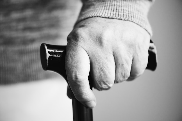 Closeup of elderly hand holding a walking stick Free Photo