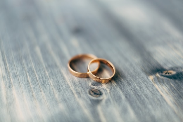 Premium Photo | Closeup of gold wedding rings on gray wooden texture ...